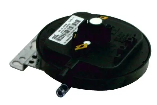 Differenzdruckwächter von Wolf, schwarze runde Bauform mit Anschluss für Druckschläuche und Platine zur elektrischen Verbindung auf der Oberseite, montiert auf metallischer Halterung.